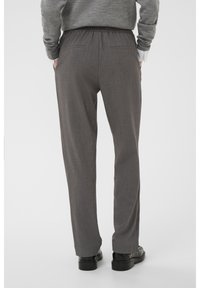 Pantalons tissés gris avec une coupe décontractée. Dotés d'une taille élastique et de deux poches arrière. Texture lisse avec un motif subtil.