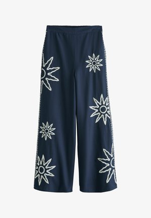 Pantaloni largi militari cu modele albe brodate de soare împrăștiate pe față și pe părți, talie elastică, croială de lungime medie.