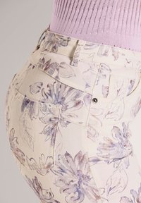 Bloemmotief spijkerbroek in crème met paarse en blauwe accenten. Heeft een aansluitend ontwerp, achterzakken en een gestructureerde tailleband.