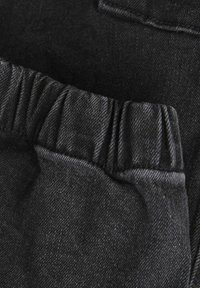 Svart denimtyg har en rynkad midja och plana fickdetaljer, med en mjuk textur och subtil färgskillnad.
