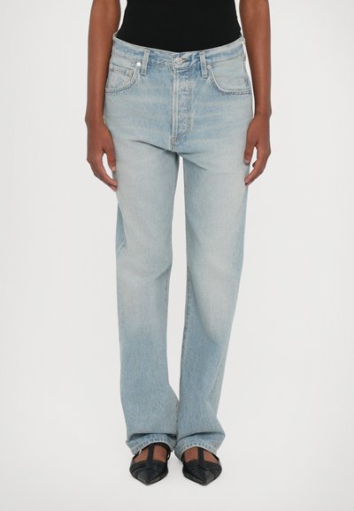 Jean taille haute bleu clair avec une coupe décontractée, cinq poches et un léger motif délavé. Le tissu a une texture denim classique.