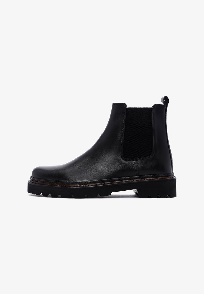 Botas Chelsea de cuero negro con paneles laterales elásticos, punta redonda y suela de goma texturizada. Detalle de costura sutil a lo largo del borde.