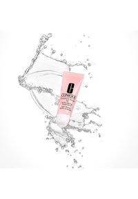 Clinique Moisture Surge läppbehandling i ett mjukt rosa rör. Har en slät finish, vit spets, omges av vattensprut.