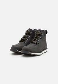 Botas negras de tobillo con cuero texturizado, puntera reforzada y suela blanca contrastante. Presentan ojales de metal y cordones duraderos en color marrón.