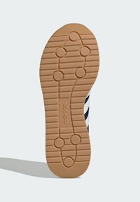 Adidas-skoled med en texturerad gummiyta, som har cirkulära greppmönster och en framträdande "adidas"-logotyp.