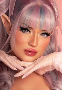 Ritratto di una persona con capelli lilla chiaro, riflessi blu, orecchie simili a quelle degli elfi, labbra rosa lucide e guanti di chiffon rosa, su uno sfondo rosa.