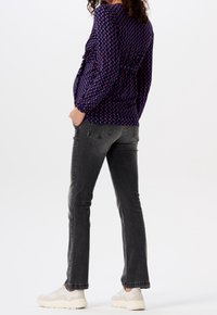 Langärmlige lila Bluse mit geometrischem Muster, kombiniert mit grauen geraden Jeans und weißen Sneakers. Lässiges Outfit, minimalistisches Design.