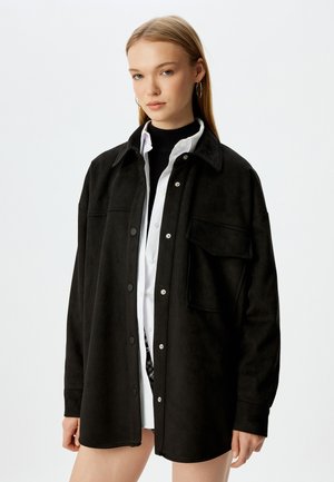 Zwarte shirtjack gemaakt van zacht, nubuck-achtig materiaal, met een kraag, drukknoopsluiting en een enkele borstzak.