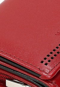 Rode leren portemonnee met een gladde textuur, voorzien van een zilveren rits, ingewikkelde perforaties en contrasterende stiksels langs de randen.