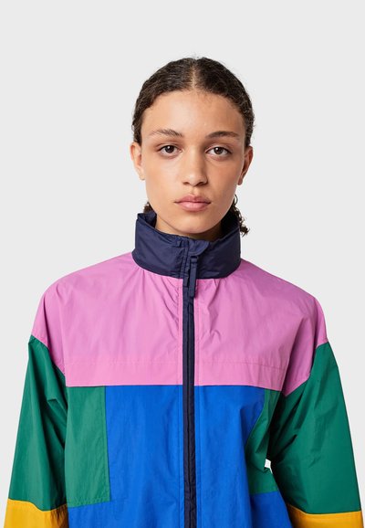 Kleurblok windbreaker jas in roze, marineblauw, groen en blauw. Beschikt over een hoge kraag, volledige rits en is gemaakt van een lichte, soepele stof.