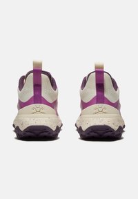 Un paio di scarpe da trail running viola e crema viste da dietro, con suole texture e linguette in tessuto sui talloni.