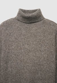 Pull en col roulé en maille brune douce et texturée. Doté d'un col haut et d'une coupe décontractée, idéal pour le superposition.