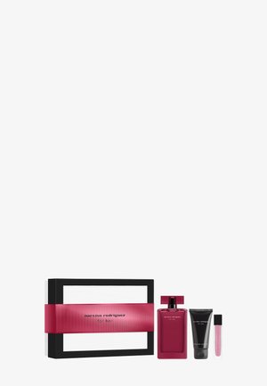 Coffret cadeau avec une boîte rectangulaire, un flacon de parfum rose, un tube de lotion noir et un petit tube de gloss à lèvres rose disposés sur un fond blanc.