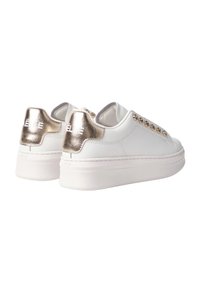 Sneakers bianchi con una finitura testurizzata, dettagli in oro metallico sul tallone e occhielli decorativi lungo il lato. Design con suola piattaforma.