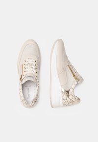 Baskets beiges en matériaux mesh et cuir, dotées de lacets, d'une fermeture éclair sur le côté et d'un accent logo texturé. Semelle blanche légère.