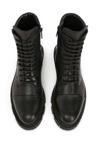 Botas de tobillo de cuero negro con punta redonda, superficie texturizada, cordones en la parte delantera y cremallera lateral. Acabado mate notable y diseño de suela robusta.