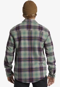 Gekruiste flanellen shirt in groene, paarse en oranje tinten. Lange mouwen, knoopmanchetten en afgeronde zoom. Zachte, gestructureerde stof.