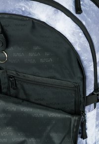 Zaino in nylon nero con un motivo astratto blu e grigio. Presenta un compartimento principale con zip e una tasca frontale con il marchio NASA.