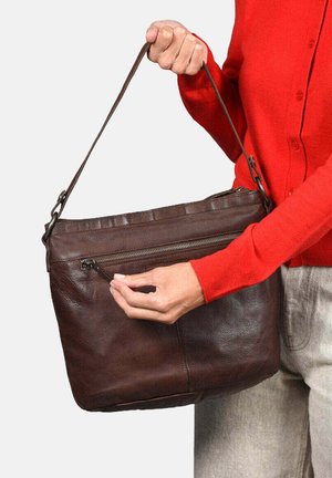 Bolso de hombro de cuero marrón con un bolsillo con cremallera, diseño plano y correa ajustable sostenida por una mano. Adecuado para el uso diario.