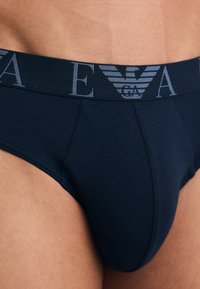 Slip in cotone blu navy con cintura elastica e dettagli logo grigi, dalla forma aderente e texture liscia.