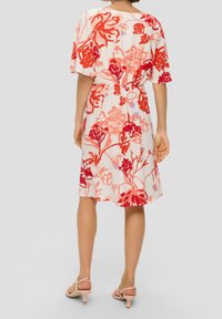 Blommönstrad klänning med en röd och rosa design på en ljus bakgrund, med korta ärmar, elastisk midja och midi-längd.