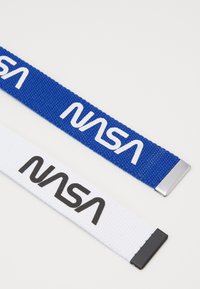 Due cinghie di tessuto intrecciato, una blu con testo "NASA" bianco e una bianca con testo "NASA" nero. Ognuna ha una punta metallica.