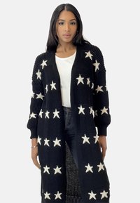 Gilet en tricot noir avec des motifs d'étoiles blanches, devant ouvert, manches longues et finition texturée.