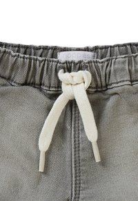 Grijze stoffen shorts met een elastische tailleband, voorzien van een witte trekkoord en een klein label met de tekst "noppies" op de tailleband.