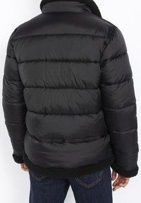 Czarna pikowana kurtka puchowa z przeszywanymi sekcjami, kołnierzem i krawędzią podszytymi polarem oraz gładką, zewnętrzną fakturą. Charakteryzuje się luźnym krojem i prostą linią.