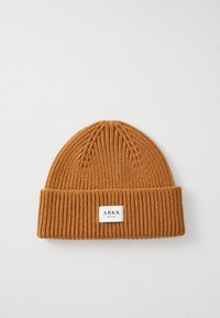Rust-colored ribbed knit beanie with folded brim and white rectangular label reading "ARKK Copenhagen" on front center.