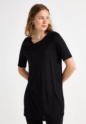Tunic nera con scollatura ampia e maniche corte, caratterizzata da una vestibilità morbida e una texture soffice. Fessure laterali sottili vicino all'orlo.