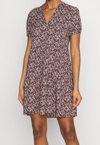 Blumenkleid mit V-Ausschnitt, kurzen Puffärmeln und lockerer Passform. Mit einem dunkelvioletten Hintergrund und kleinen, mehrfarbigen Blumenmustern.