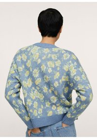 Gestrickter Pullover in Hellblau mit floralem Muster in Grün und Gelb. Verfügt über einen runden Ausschnitt sowie gerippte Bündchen und Saum.