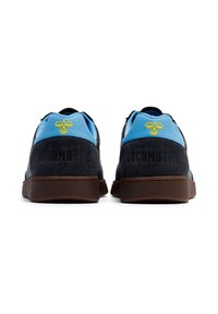 Sapatos de atletismo azul escuro com um calcanhar azul claro, apresentando um logótipo de abelha amarelo e o texto "EL PASO LOCOMOTIVE FC", sola de borracha castanha.