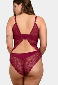 Ensemble de lingerie en dentelle bordeaux avec des motifs géométriques, des bords festonnés et des sections semi-transparentes, doté de bretelles ajustables et d'une fermeture à crochet.