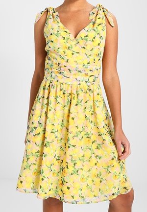 Vestido amarillo sin mangas con estampado floral, tirantes ajustables con lazo, escote en V, cintura fruncida ajustada y falda acampanada hasta la rodilla.