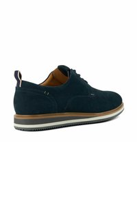 Chaussure en suede bleu foncé avec un bout rond, un profil mince et une semelle claire contrastante. Dotée d'une languette en boucle à l'arrière pour un enfilage facile.