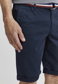 Tamna plava pamučna kratka hlače s prevrnutim rubovima, s ravnim prednjim dijelom i elastičnom strukom, uparenim s remenom u više boja s uzorkom pruga.