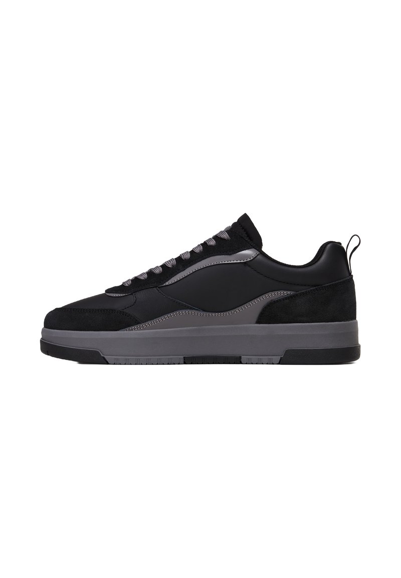 Scarpe da ginnastica nere realizzate con una combinazione di materiali in pelle e suede, dotate di accenti grigi, una suola intermedia testurizzata e lacci rotondi.