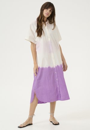 Vestido camisero con botones que presenta una parte superior blanca que se transforma en una parte inferior sólida púrpura. Mangas cortas, aberturas laterales y tejido ligero.