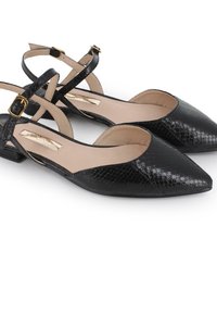 Zapatos negros de punta con un acabado texturizado, que cuentan con correas en el tobillo y un pequeño tacón bloque. El interior es de un tono beige claro con una textura suave.