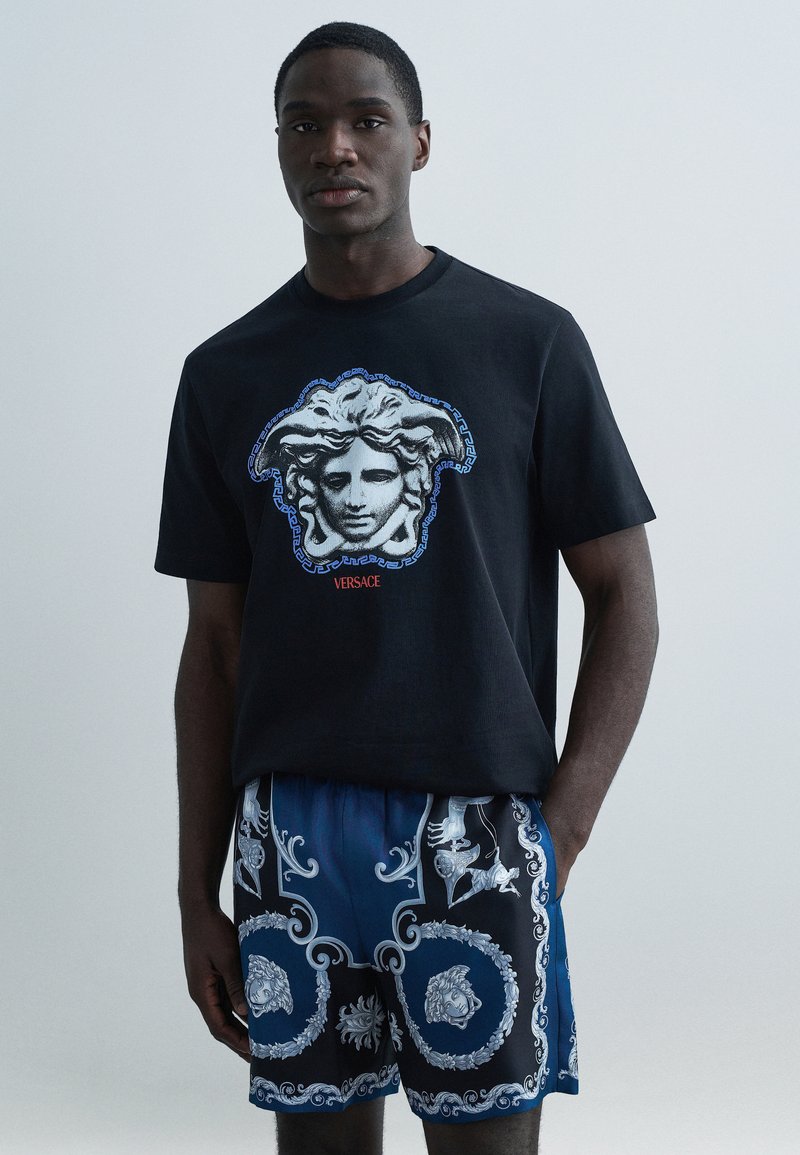 Czarny bawełniany t-shirt z grafiką Meduzy i niebieskimi akcentami. W zestawie wzorzyste niebieskie spodenki z misternymi srebrnymi wzorami.