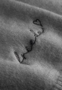 Zachte stof met geborduurde cursieve woorden "liefde" die eindigt in een hartvorm, weergegeven inclose-up met zichtbare textuurvezels.