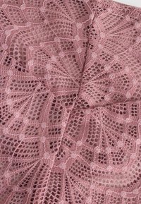 Spitzenstoff in staubigem Rosenholz, mit einem komplizierten Muster aus offenen Webarten und kreisförmigen Motiven. Weiche Textur mit detaillierten Stickereien.