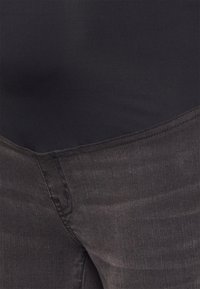 Jeans pretos com um design elegante, exibindo uma textura suave e um desbotamento subtil. Apresenta uma cintura padrão e detalhes de costura mínimos.