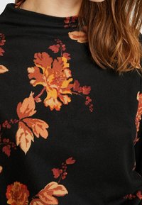 Czarny sweter z tkaniny z dużymi pomarańczowymi i żółtymi wzorami kwiatowymi, o miękkiej teksturze i zaprojektowanym dekolcie w stylu luźnym.