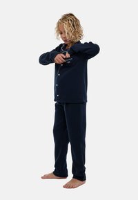 Ensemble de pyjama bleu marine, fabriqué en tissu doux, comprenant un haut boutonné avec une poche poitrine et un pantalon assorti. Sans motifs ni ornements.