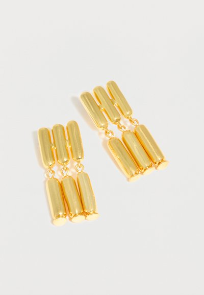 Σκουλαρίκια σε χρυσό τόνο με έξι επιμήκη οβάλ τμήματα τοποθετημένα σε δύο κάθετες σειρές, που αντανακλούν το φως σε λευκό φόντο.