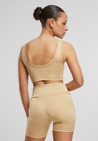 Tan cropped tank topp og matchende shorts, laget av glatt stoff, med rund halslinning og høyt liv-design med enkel søm.