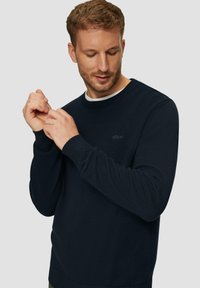 Dunkelblauer Strickpullover mit Rundhalsausschnitt und gerippten Bündchen. Subtiles Logo auf der Brust, strukturiertem Stoff und einem lässigen Schnitt.